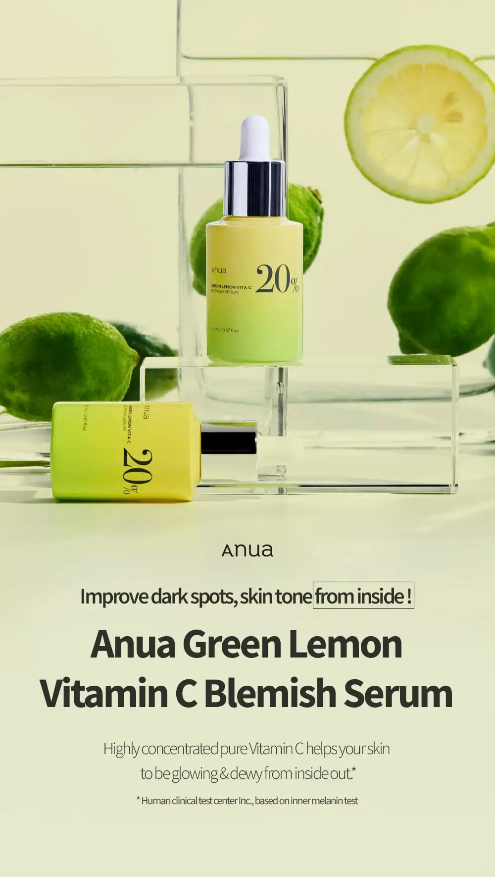 Two yellow and green gradient bottles of Anua Green Lemon Vitamin C Blemish Serum 20ml with silver caps displayed alongside fresh lemons and limes on clear acrylic blocks against a light green background.