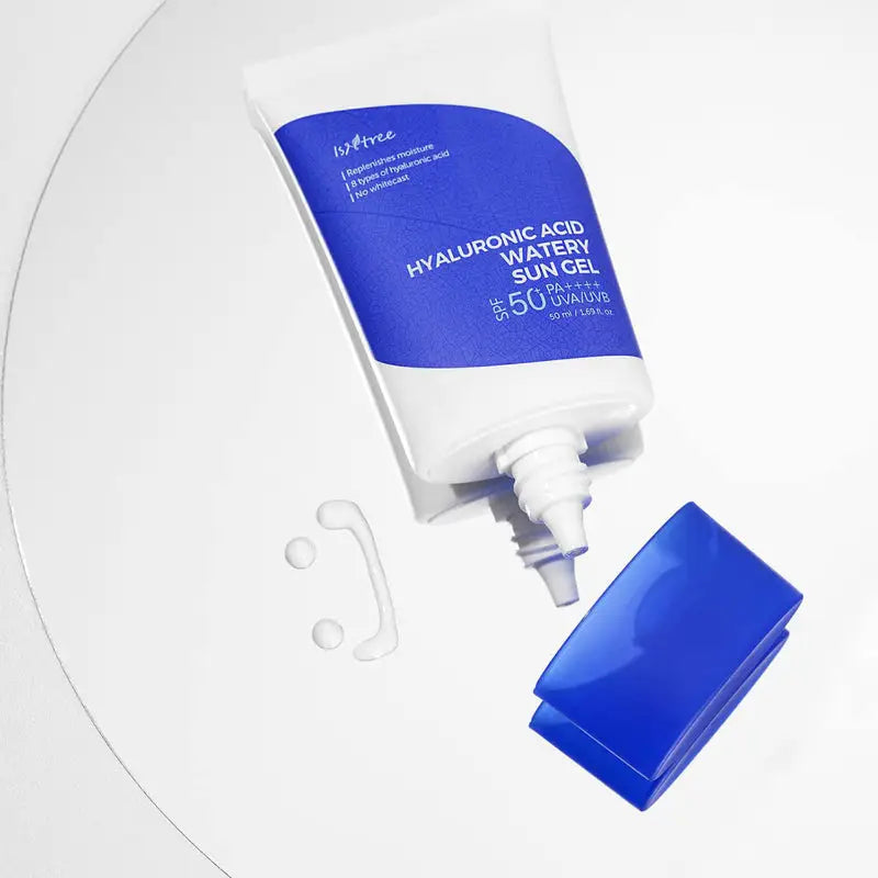 Isntree Hyaluronic Acid Watery Sun Gel 50 ml opened with clear gel drops on a white surface, featuring a blue and white tube with the cap beside it.
