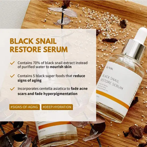 Clear glass bottle with silver dropper cap and white label with orange accents for iunik black snail restore serum rich in black snail mucin and hyaluronic acid