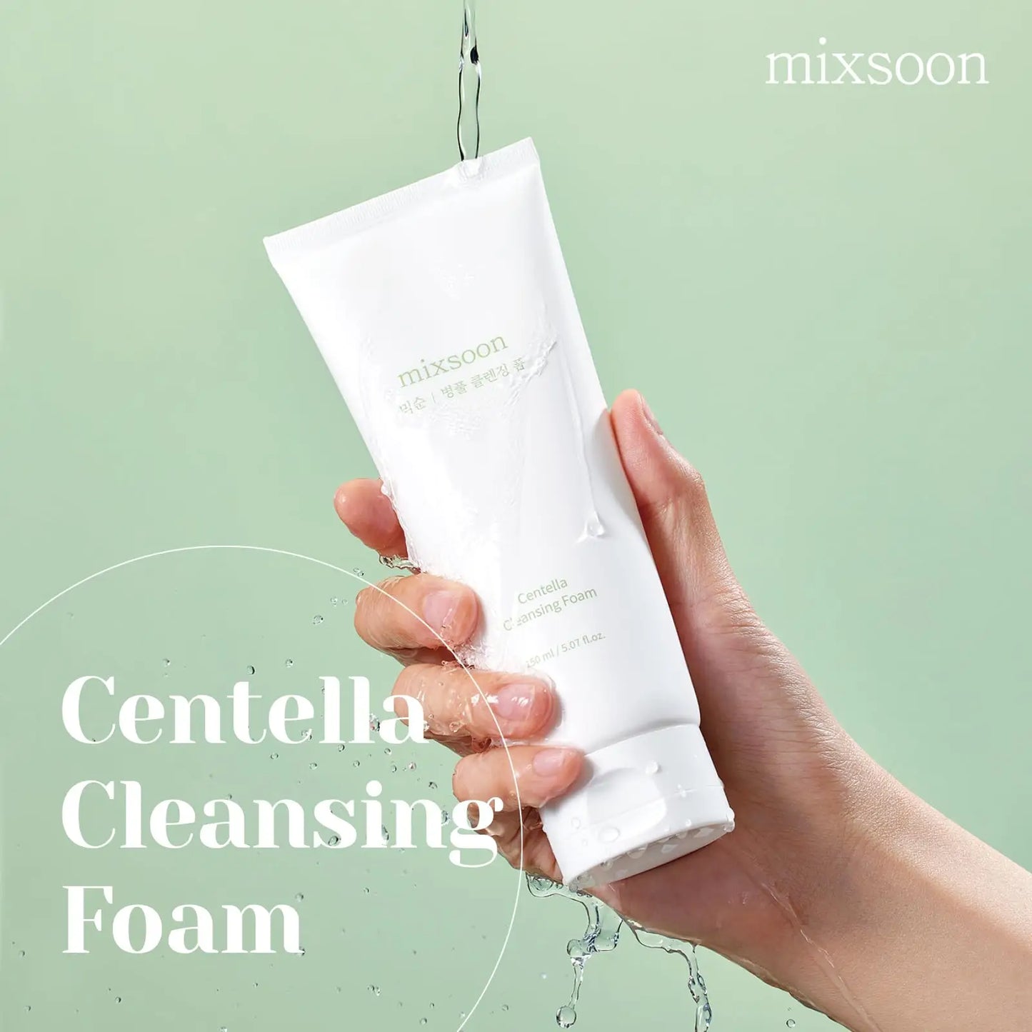 Hand holding a white tube of Mixsoon Centella Cleansing Foam 150ml with water pouring over it against a light green background, emphasizing freshness and hydration.