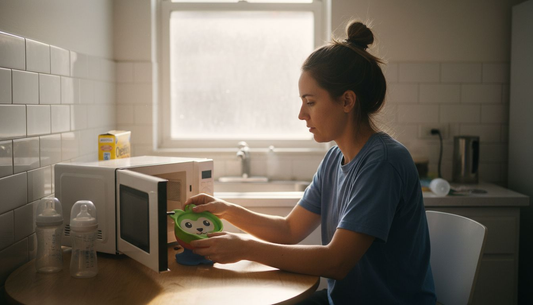 Mother placing baby bowl in kitchen microwave