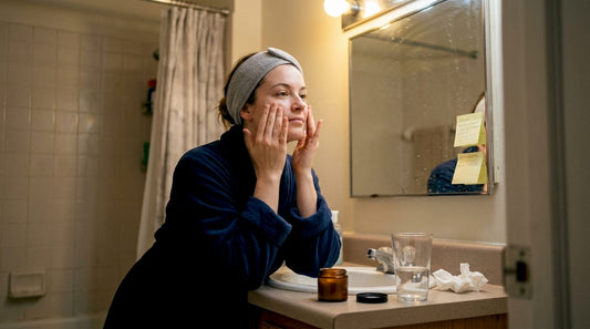 Woman applying moisturizer in small bathroom
