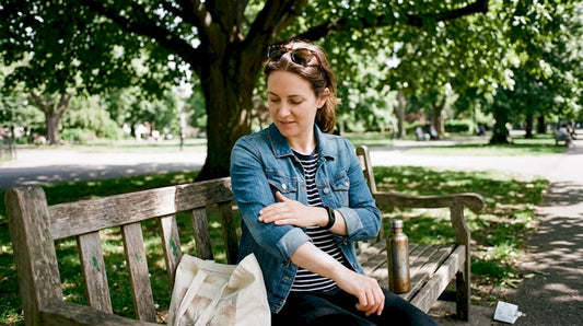 Woman applies sunscreen on park bench in sunlight