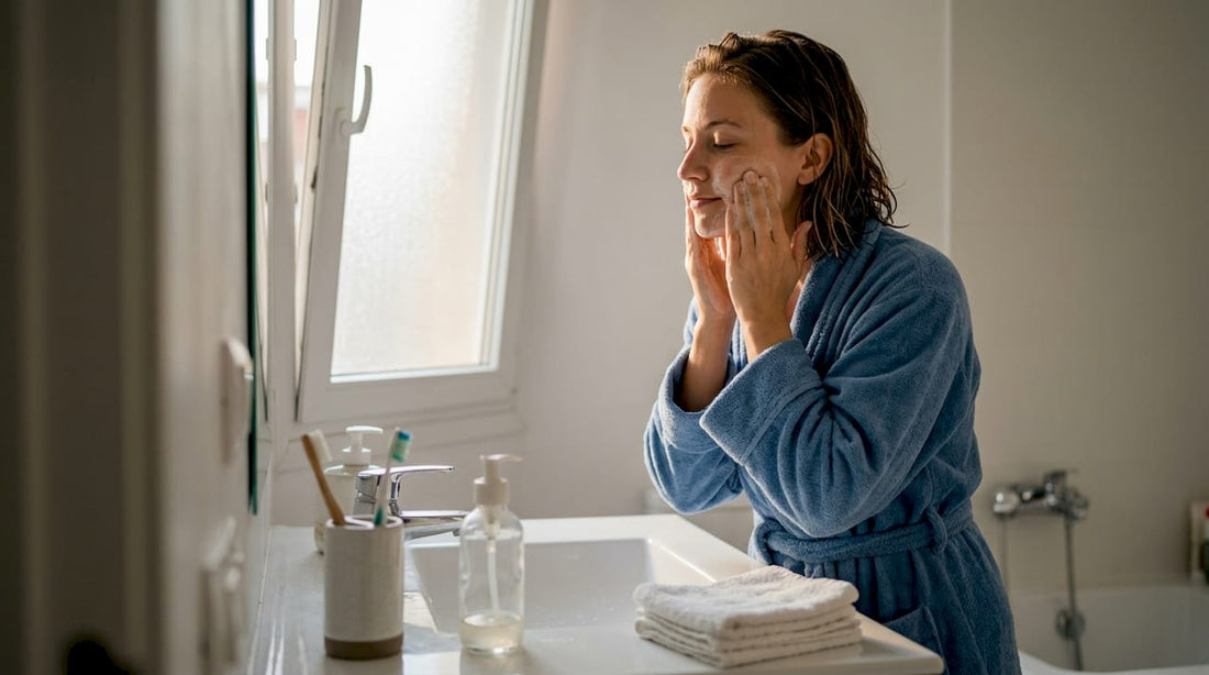 Woman cleanses face at sunlit bathroom sink