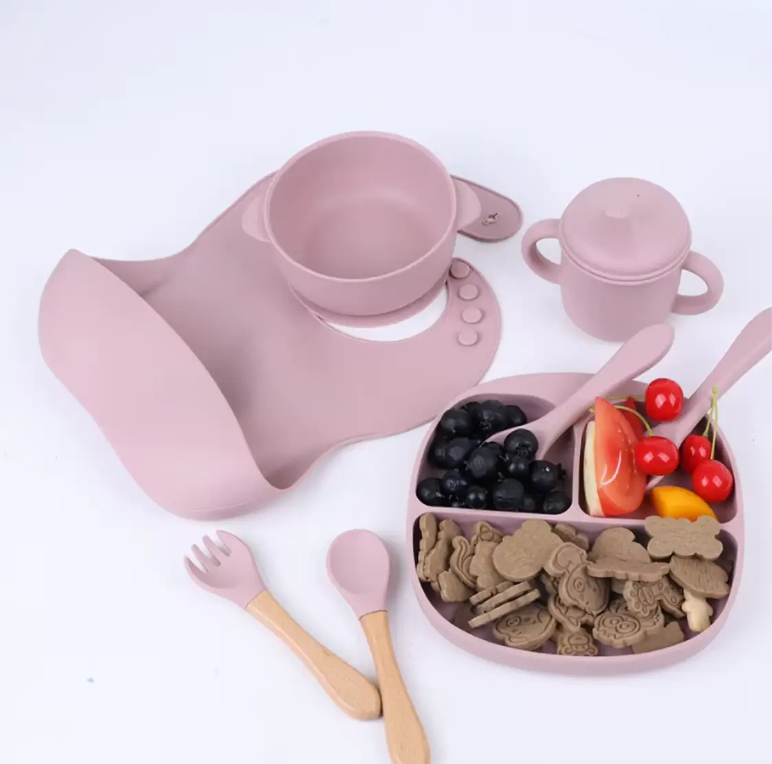 Pink children's tableware set including cup, bowl, spoon, fork, and snack tray on a white background.