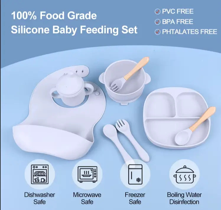 Silicone baby feeding set with bib, bowl, cup, and utensils on a blue background