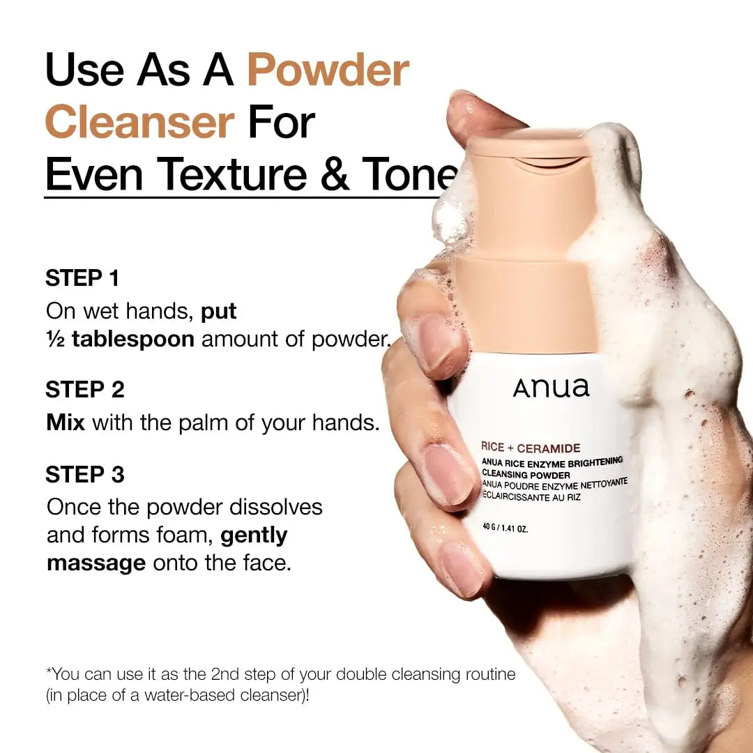Hand holding a foaming bottle of Anua Rice Enzyme Brightening Cleansing Powder 40g with usage instructions for applying as a powder cleanser for even texture and tone.