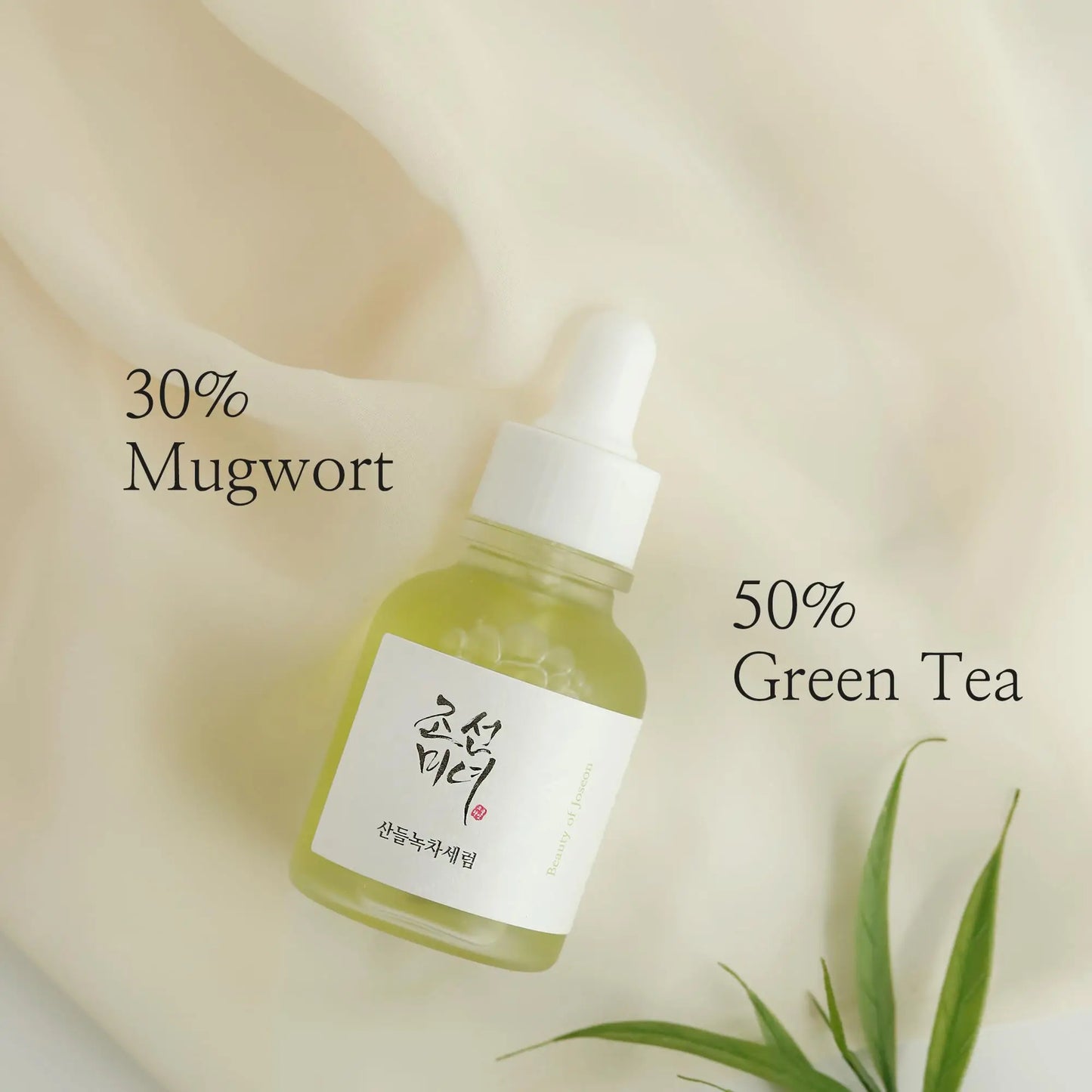 Beauty of Joseon Calming Serum Green Tea Panthenol 30ml in a glass dropper bottle highlighting 50% green tea and 30% mugwort ingredients on a soft cream-colored fabric background with green leaves.