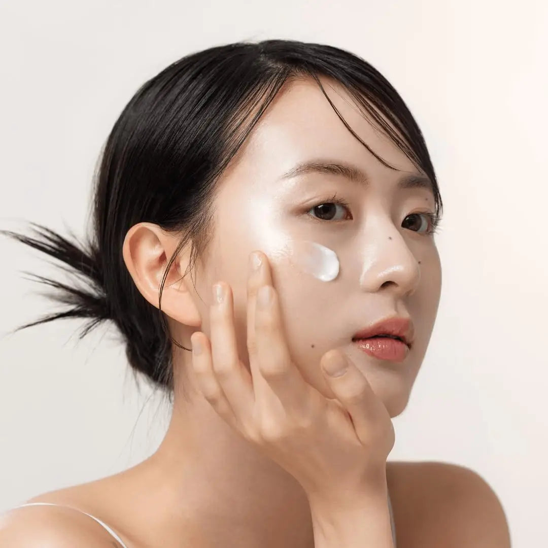 Woman with smooth skin gently applying Beauty of Joseon Dynasty Cream 100ml on her cheek, showcasing radiant and hydrated facial skin care.