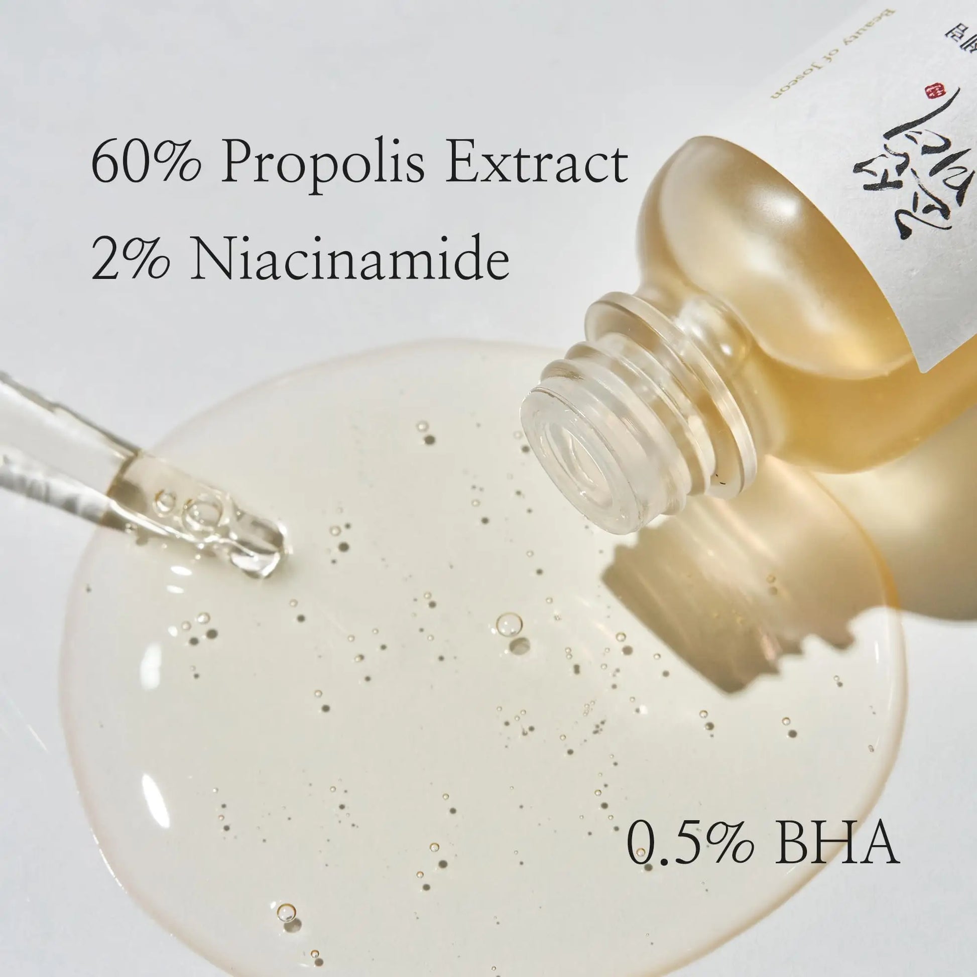 Beauty of Joseon Glow Serum Propolis and Niacinamide 30ml bottle tilted with serum dropper and clear gel serum pooled on white surface showing key ingredients 60% propolis extract, 2% niacinamide, and 0.5% BHA.