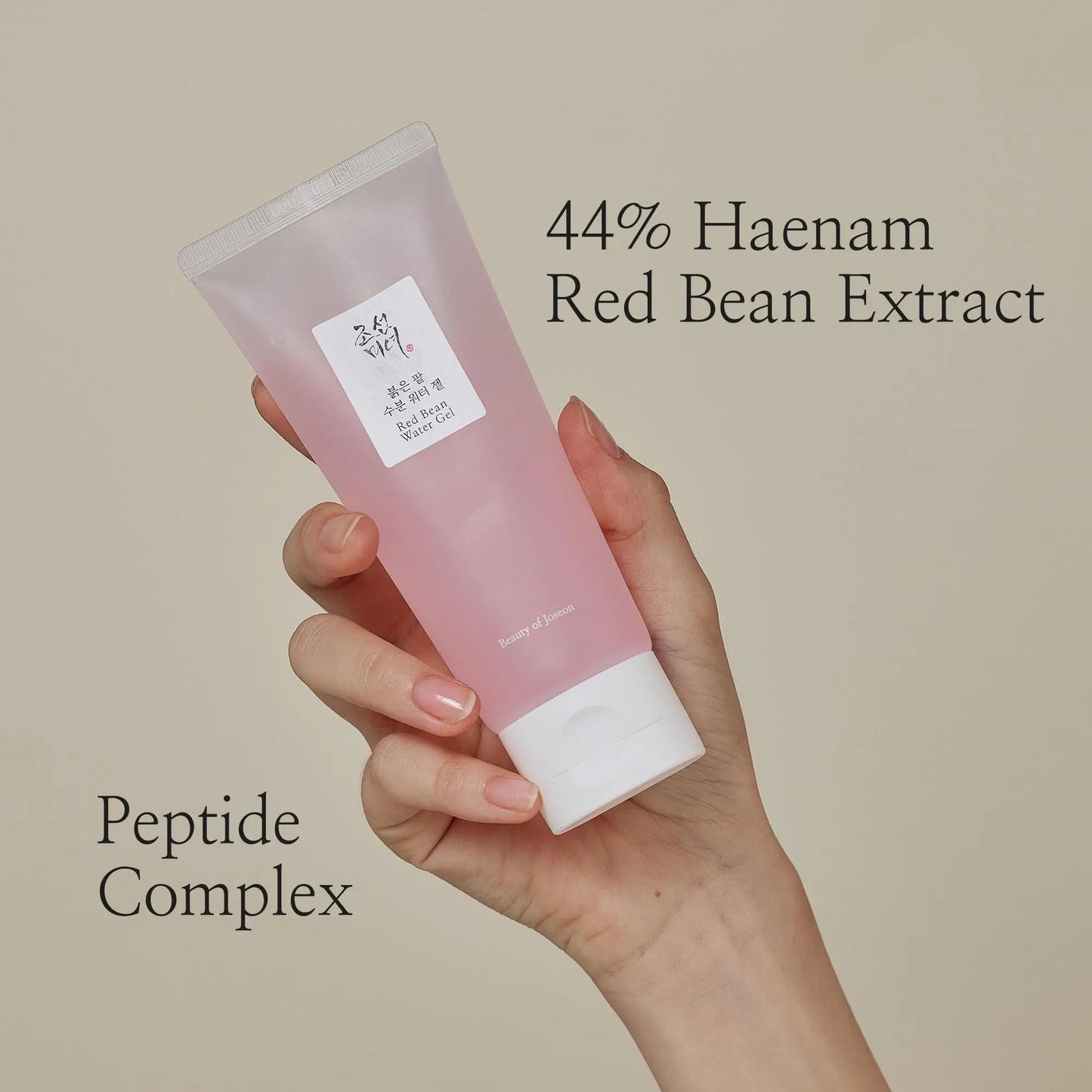 Hand holding a tube of Beauty of Joseon Red Bean Water Gel 100ml with text highlighting 44% Haenam Red Bean Extract and Peptide Complex on a neutral background
