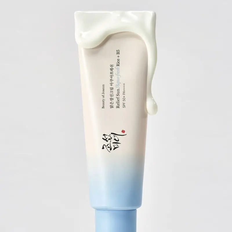 Tube of Beauty of Joseon Relief Sun Aqua-Fresh : Rice + B5 sunscreen with creamy texture dripping over the top against a plain background