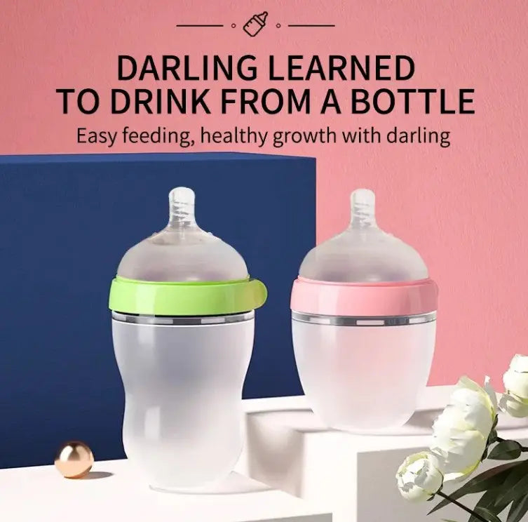 Two BPA Free Anti Colic Silicone Breastfeeding Bottles with adjustable flow teats in green and pink caps are displayed against a pink and blue backdrop with white roses nearby.