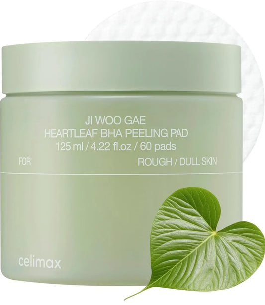 celimax Ji.Woo.Gae Heartleaf BHA Peeling Pad (60 Pads) in a light green container with a heartleaf plant beside it and a peeling pad in the background for rough and dull skin care.
