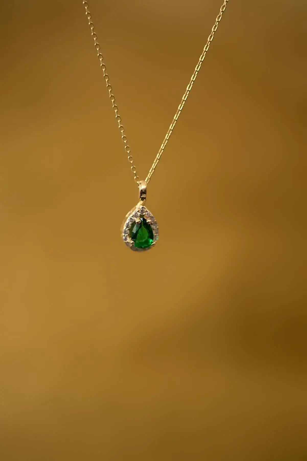 Einzelstück - 14K Gold Plated Emerald Drop Necklace - Emerald water drop Necklace - Gold Necklaces Gift for Women featuring a delicate gold chain with a teardrop-shaped green emerald pendant surrounded by small clear stones.