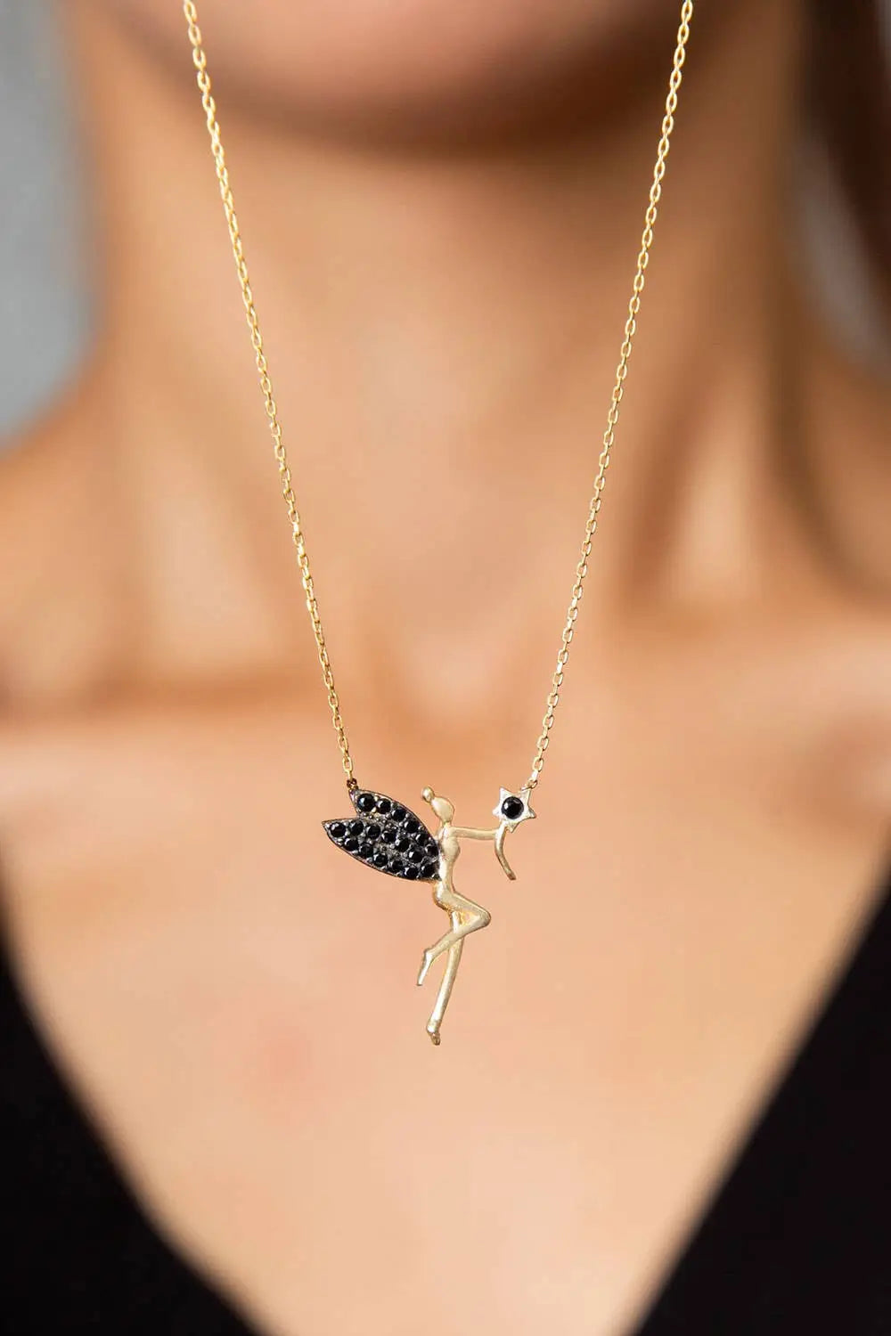 Einzelstück - 14K Gold Plated Fairy Necklace with Black Zircona stones - Fairy Gold Necklace - Gold Necklaces Gift for Women worn on a woman's neck, featuring a delicate fairy pendant with black zirconia wings and a star.
