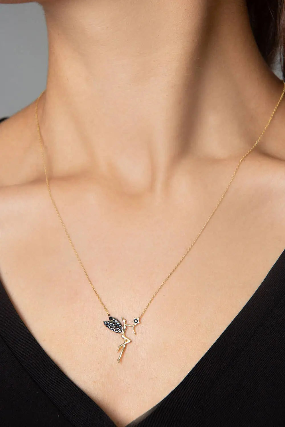 Close-up of a gold necklace worn on a woman's neck featuring a delicate fairy pendant with black zirconia stones in a minimalist style, Einzelstück - 14K Gold Plated Fairy Necklace with Black Zircona stones - Fairy Gold Necklace - Gold Necklaces Gift for Women.