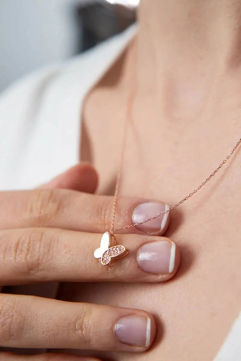 Close-up of a person holding a delicate butterfly pendant necklace on a thin chain, showcasing the Einzelstück - 14K Gold Plated Farfalle Necklace - Butterfly pendant Necklace - Gold Necklaces Gift for Women.