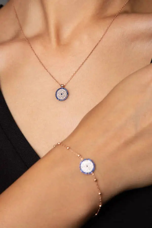 Einzelstück - 14K Gold Plated Nazar Rose Gold Bracelet with blue zircona crystals - Rose Gold Bracelet- Gold Bracelet Gift for Women worn on wrist with matching pendant necklace on model in black top.