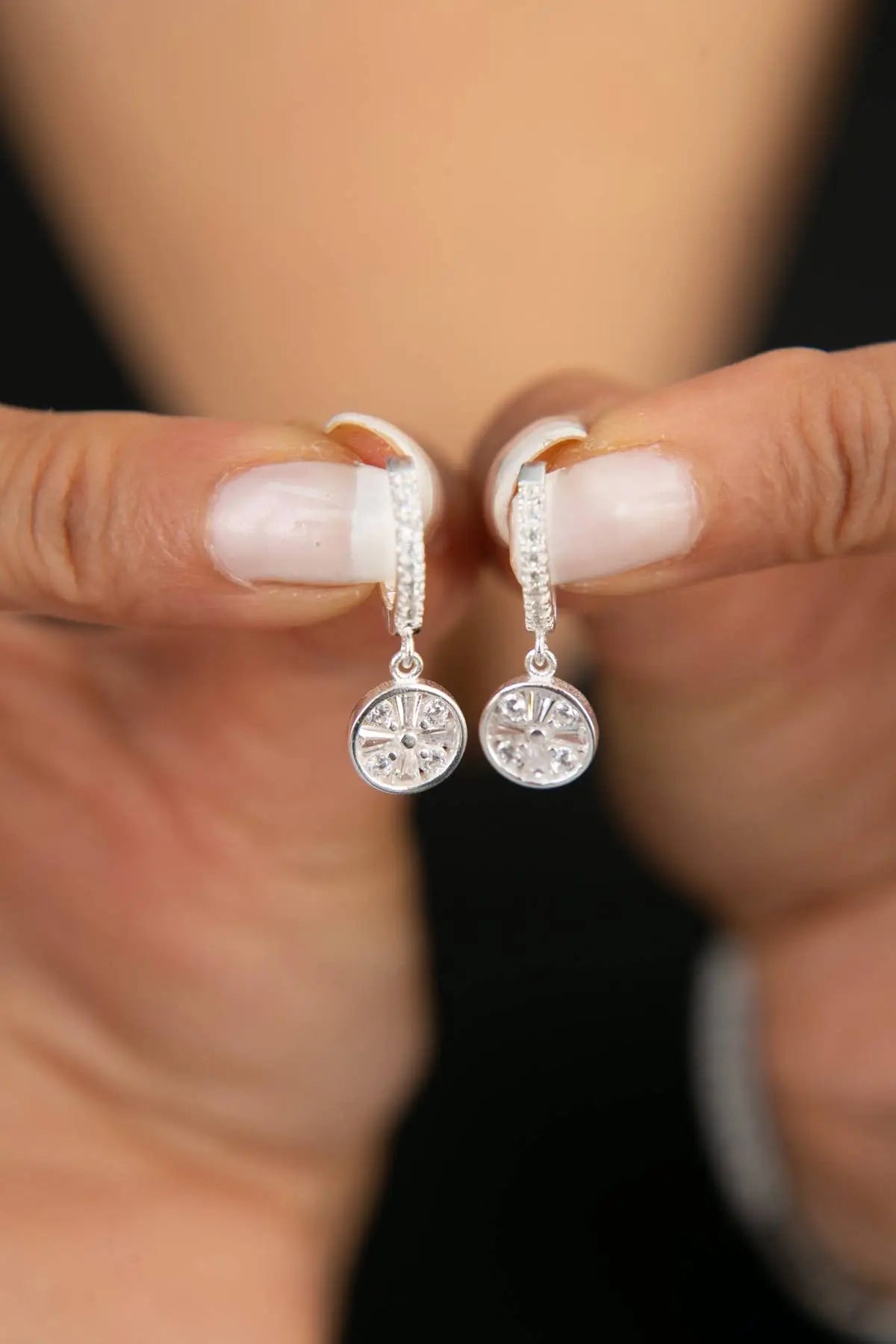 Close-up of a pair of Einzelstück - Mandala Silver Earrings - Silver Earrings- Earrings Gift for Women held between two fingers, featuring intricate mandala design and sparkling detail.