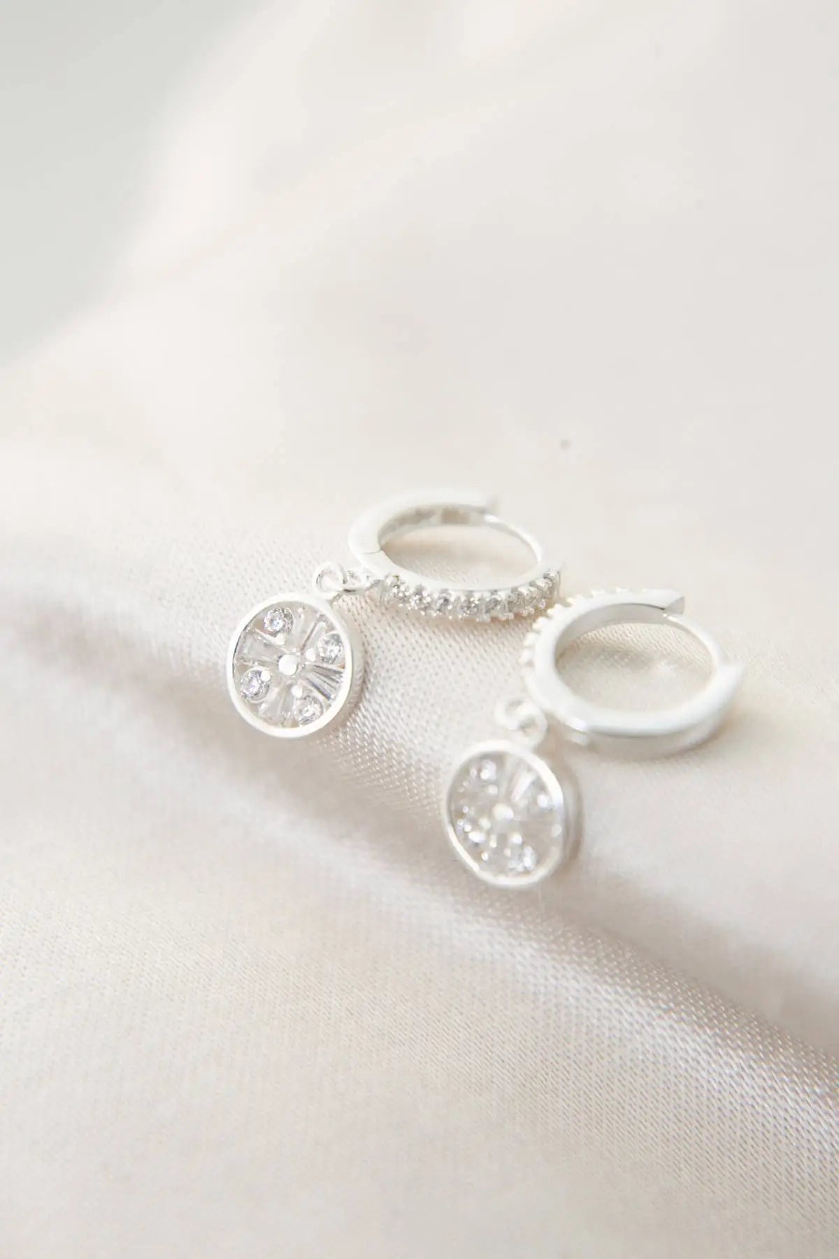 Close-up of Einzelstück - Mandala Silver Earrings - Silver Earrings- Earrings Gift for Women featuring delicate silver hoops with intricate mandala-inspired dangle charms decorated with small clear stones.