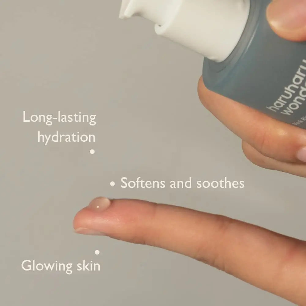 Close-up of a hand dispensing haruharu wonder Black Rice Hyaluronic Essence 50 ml, highlighting benefits including long-lasting hydration, softening and soothing, and glowing skin.