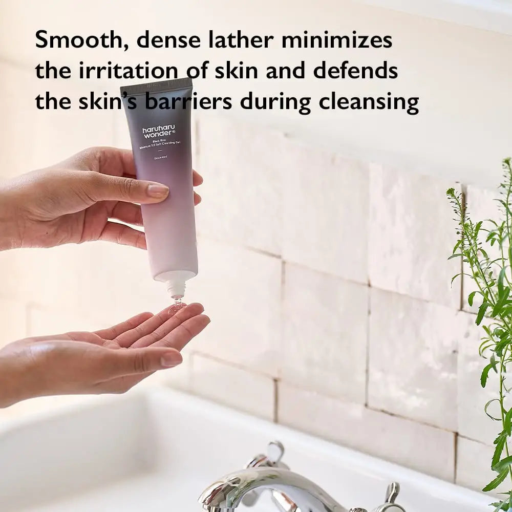 Hand holding and dispensing haruharu wonder Black Rice Moisture 5.5 Soft Cleansing Gel 100ml over the other hand above a bathroom sink with text highlighting gentle cleansing benefits.