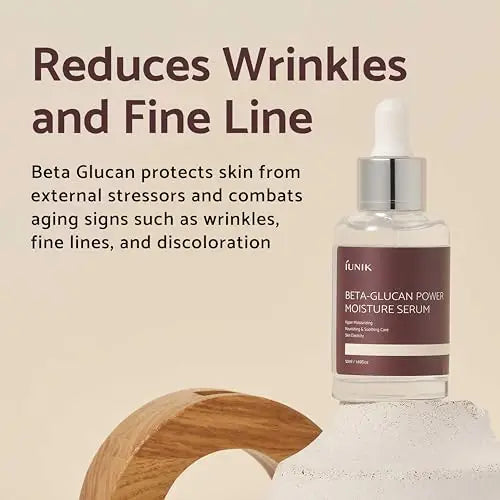 Bottle of iUNIK Beta Glucan Power Moisture Serum 50ml with dropper on a textured surface, accompanied by text highlighting its benefits for reducing wrinkles and fine lines.