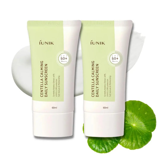 Two tubes of iUNIK Centella Calming Daily Sunscreen 60ml, Pack of 2, with SPF 50+ protection, displayed with centella leaves and a cream swatch for soothing skin care.