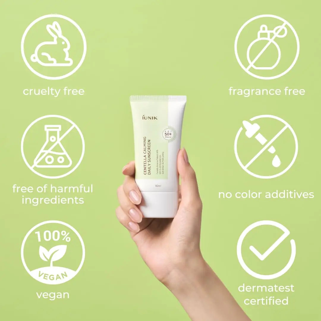 Hand holding a tube of iUNIK Centella Calming Daily Sunscreen 60ml, Pack of 2, surrounded by icons indicating cruelty free, fragrance free, free of harmful ingredients, no color additives, 100% vegan, and dermatest certified.