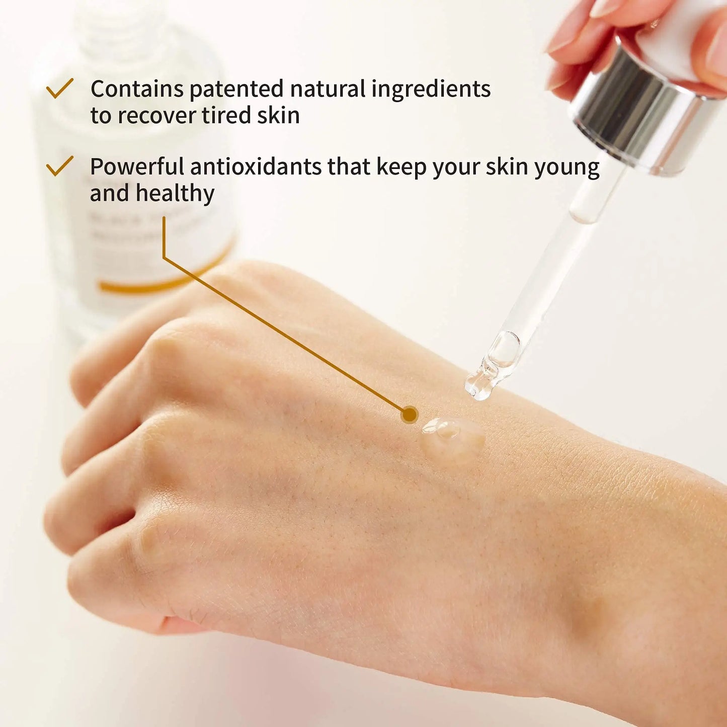 Close-up of a hand with a dropper applying serum, highlighting benefits of iUNIK Centella Calming Gel Cream 60ml + iUNIK Black Snail Restore Serum 50ml including natural ingredients and antioxidants for skin recovery and youthfulness.