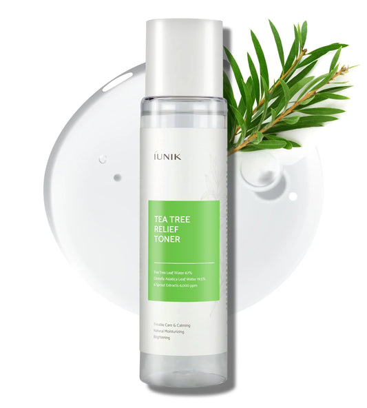 Bottle of iUNIK Tea Tree Relief Toner 200ml with green label next to a clear liquid droplet and fresh tea tree leaves on white background.