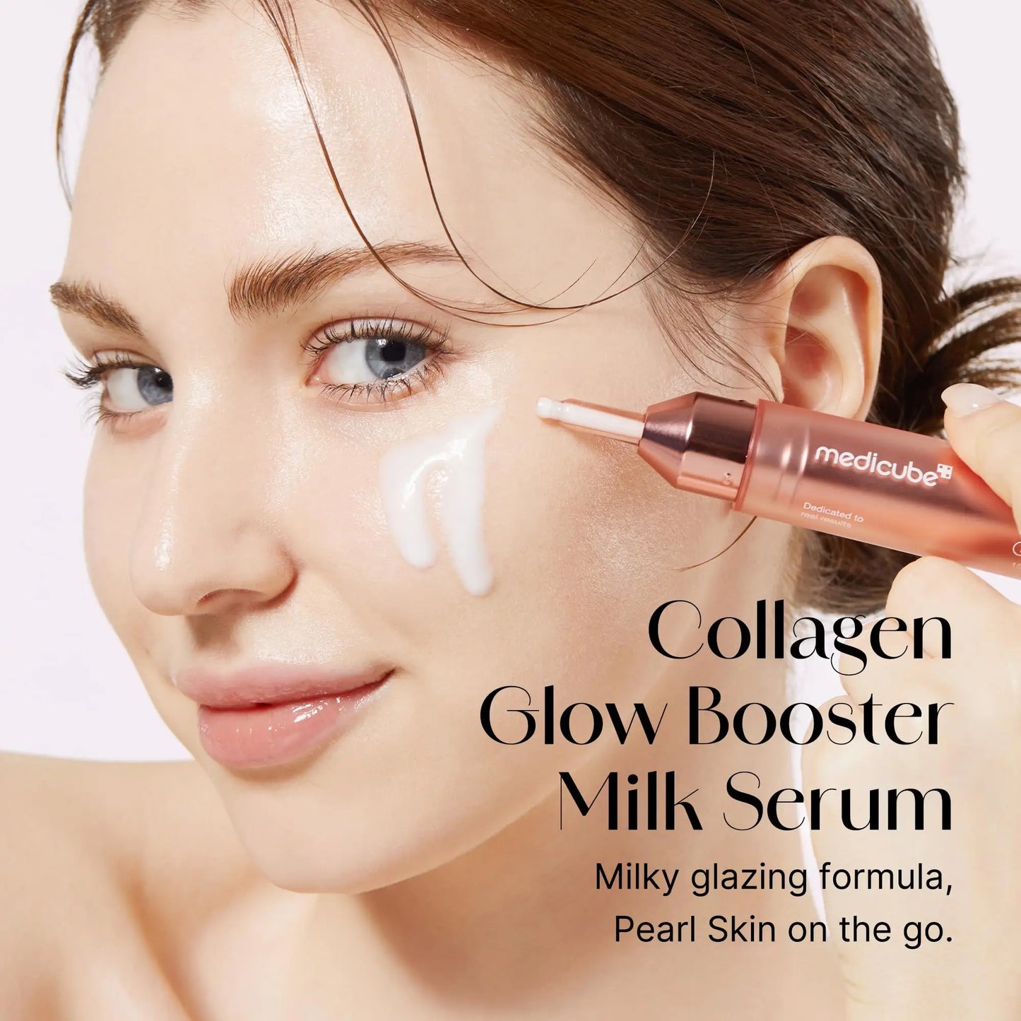 Woman applying medicube Collagen Glow Booster Serum 15ml with creamy white serum on her cheek, showcasing radiant and glowing skin.