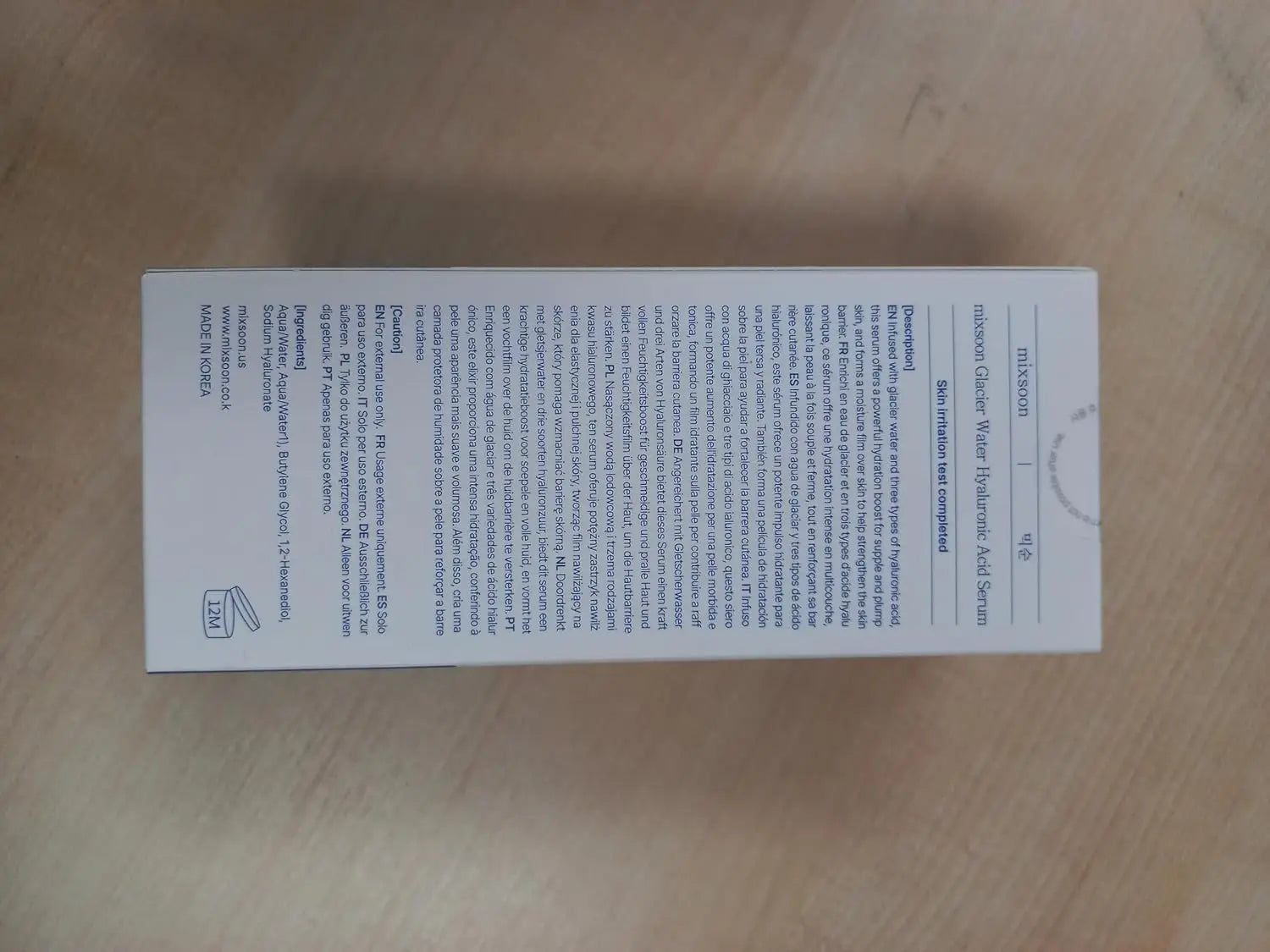 Back view of Mixsoon Glacier Water Hyaluronic Acid Serum 300ml product packaging, showing detailed ingredient and usage information on a beige surface.