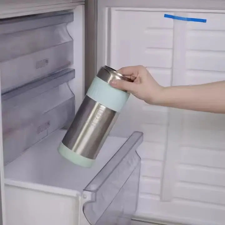 Hand placing a stainless steel vacuum-insulated bottle with a light blue silicone grip inside a refrigerator, showcasing the Portable Breast Milk and Water Cooler 24-Hour Extended Cooling | Ice-Free Portable Milk Storage for Travel and Work | All-in-One Ice-Free Cooler and Baby Bottle.