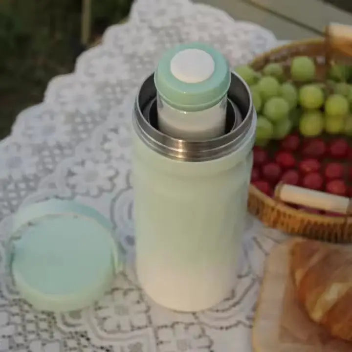 Sunlit Portable Breast Milk and Water Cooler 24-Hour Extended Cooling | Ice-Free Portable Milk Storage for Travel and Work | All-in-One Ice-Free Cooler and Baby Bottle on lace tablecloth with fruit basket and croissant nearby