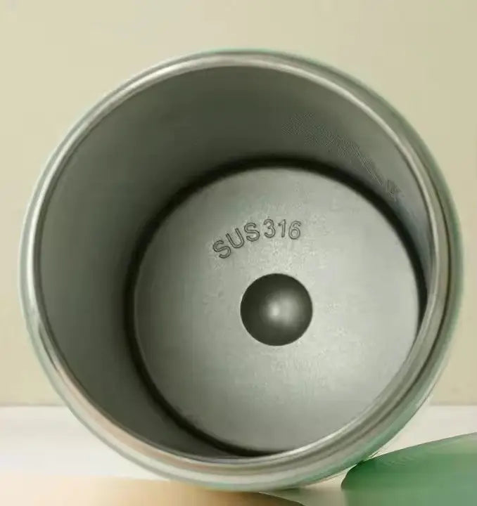 Interior view of stainless steel container marked SUS316 from the Portable Breast Milk and Water Cooler 24-Hour Extended Cooling | Ice-Free Portable Milk Storage for Travel and Work | All-in-One Ice-Free Cooler and Baby Bottle shown with a green lid beside it.