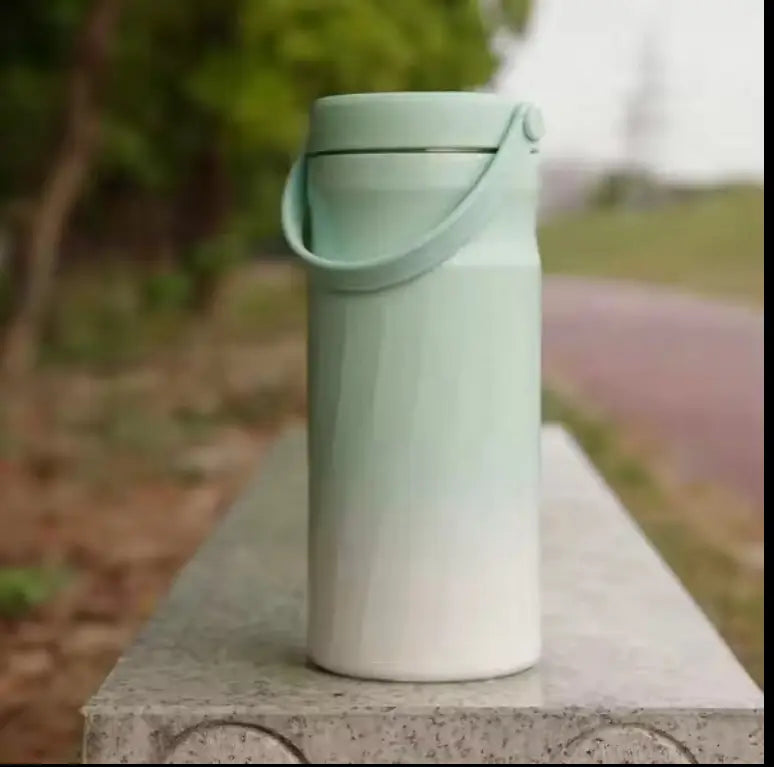 Portable Breast Milk and Water Cooler 24-Hour Extended Cooling | Ice-Free Portable Milk Storage for Travel and Work | All-in-One Ice-Free Cooler and Baby Bottle in a sleek green gradient design, placed outdoors on a stone bench.