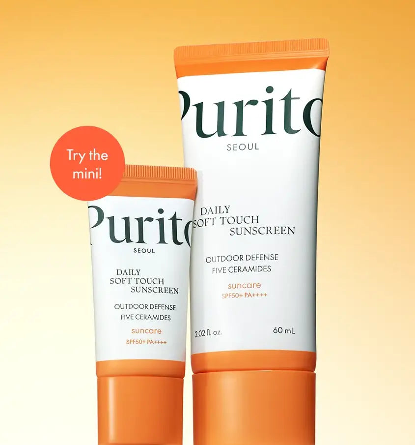 Two tubes of PURITO Daily Soft Touch Sunscreen in different sizes with orange and white packaging, promoting a mini version against a soft orange background.