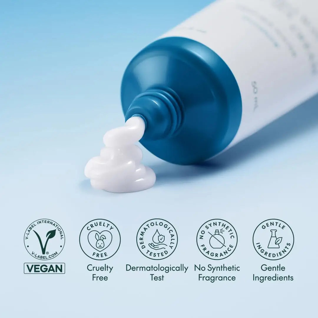 Close-up of white creamy cream flowing from a blue-topped tube of PURITO HydroWave Deep Sea Cream 50ml on a light blue background, highlighting vegan, cruelty-free, dermatologically tested, no synthetic fragrance, and gentle ingredients.