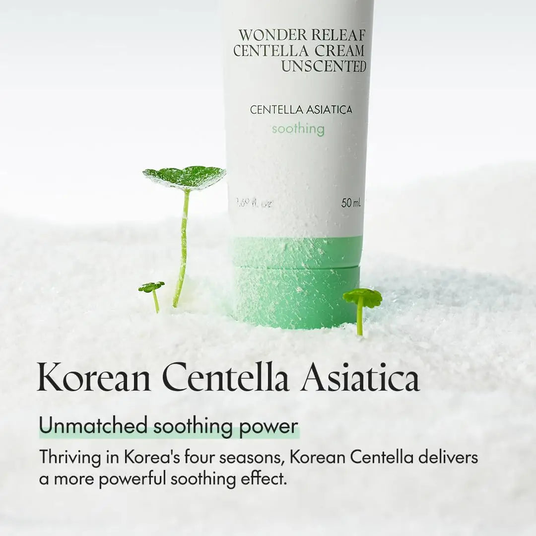 PURITO Wonder Releaf Centella Cream Unscented tube with green cap placed on white textured surface surrounded by small green centella asiatica leaves highlighting soothing skincare benefits.