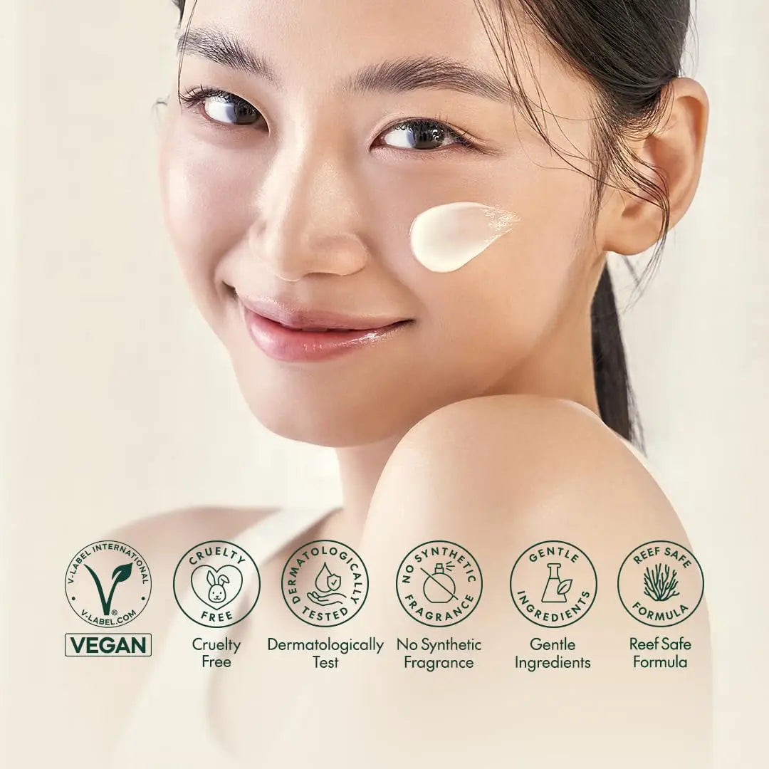 Close-up of smiling woman with cream on cheek showing smooth skin, highlighting PURITO Wonder Releaf Centella Daily Sun Lotion's gentle, vegan, cruelty-free, dermatologically tested, fragrance-free, and reef-safe qualities.