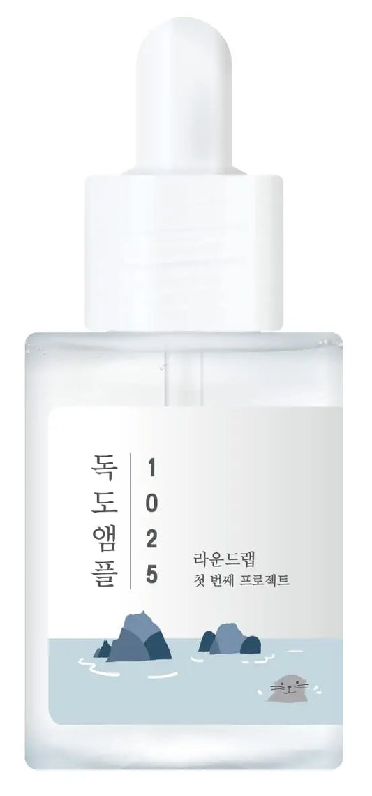 Transparent dropper bottle of ROUND LAB 1025 Dokdo Ampoule Serum 45g with minimalist design featuring small rocks and a swimming seal illustration on the label.