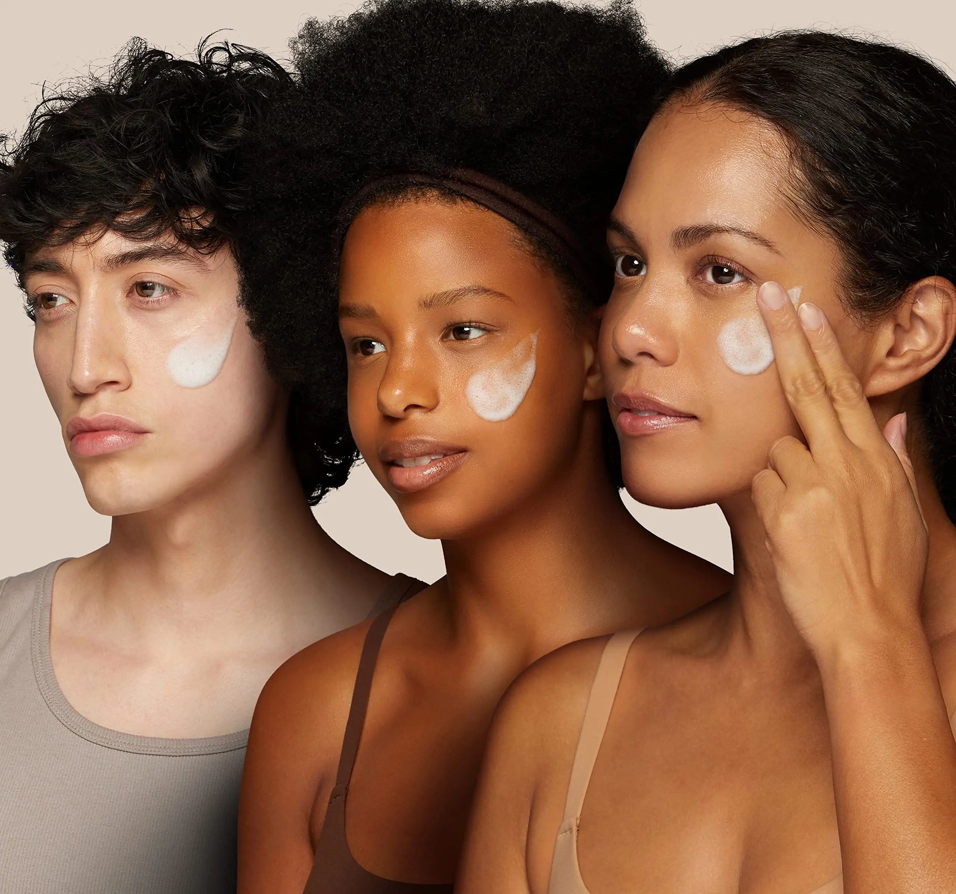 Three diverse models with glowing skin applying ROUND LAB 1025 Dokdo Cleanser 150ml cream on their cheeks, demonstrating gentle skincare use.