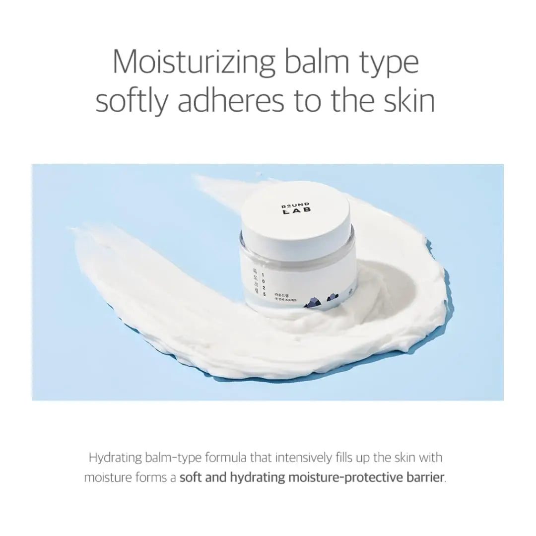ROUND LAB 1025 Dokdo Cleanser 150ml + Dokdo Cream 80ml moisturizing balm type cream jar on blue background with white cream texture spread, emphasizing soft hydration and moisture barrier.
