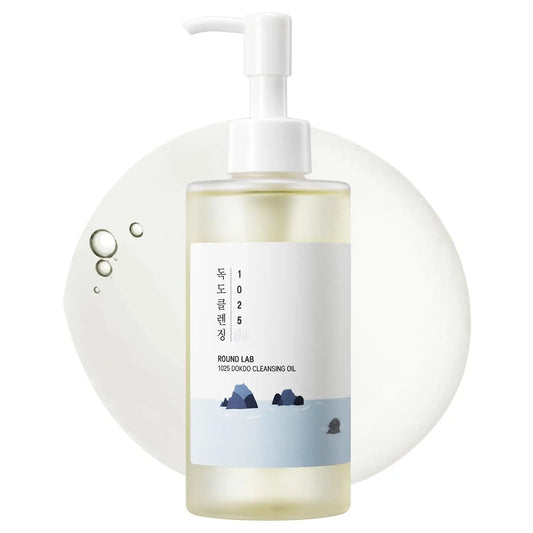 ROUND LAB 1025 Dokdo Cleansing Oil 200ml in a clear pump bottle with minimalist label showing ocean rocks, placed over a translucent cleansing oil droplet background.