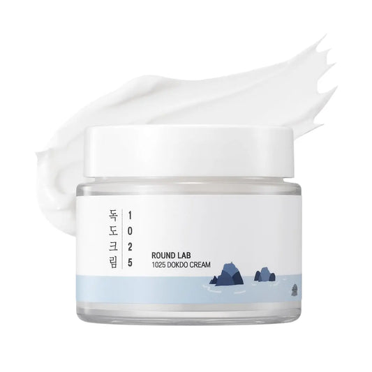 ROUND LAB 1025 DOKDO CREAM 80ml in a transparent jar with a white lid and blue ocean-inspired design, showing a smooth white cream texture behind it.