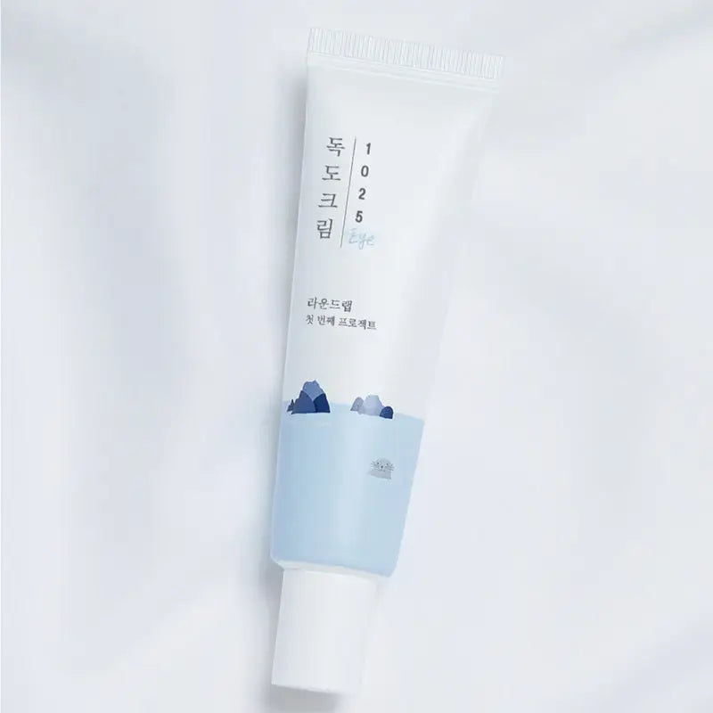Tube of Round Lab 1025 Dokdo Eye cream 30ml with minimalist white and light blue packaging featuring mountain illustrations on a plain background.