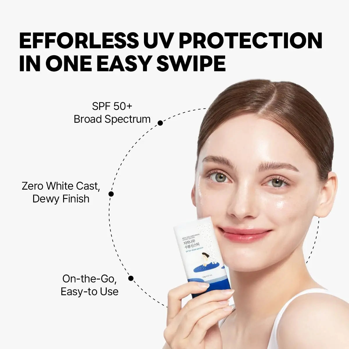 A smiling woman holding a tube of ROUND LAB Birch Juice Moisturizing Sun Stick 19g with text highlighting its SPF 50+ broad spectrum protection, zero white cast, dewy finish, and easy-to-use on-the-go application.