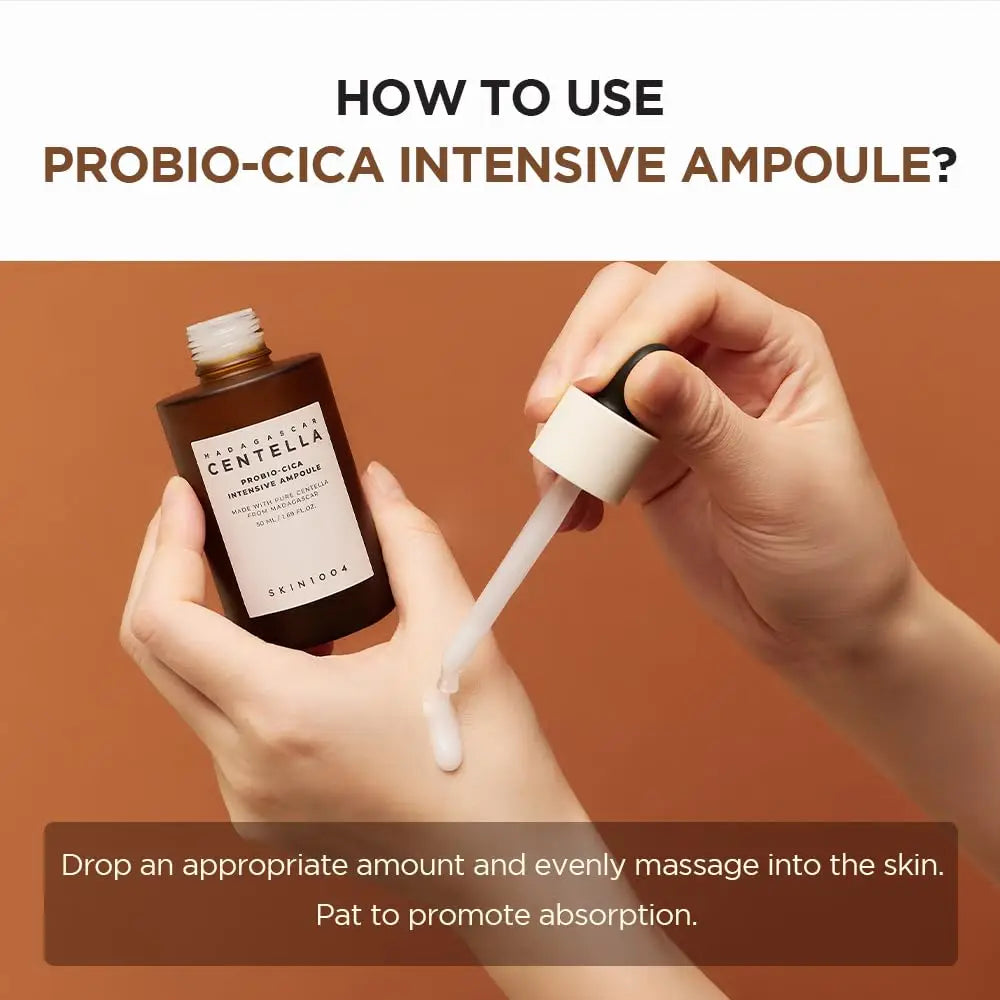 A person holding Skin 1004 Madagascar Centella Probio-Cica Intensive Ampoule 95ml with a dropper applying the ampoule on the back of their hand against a brown background.